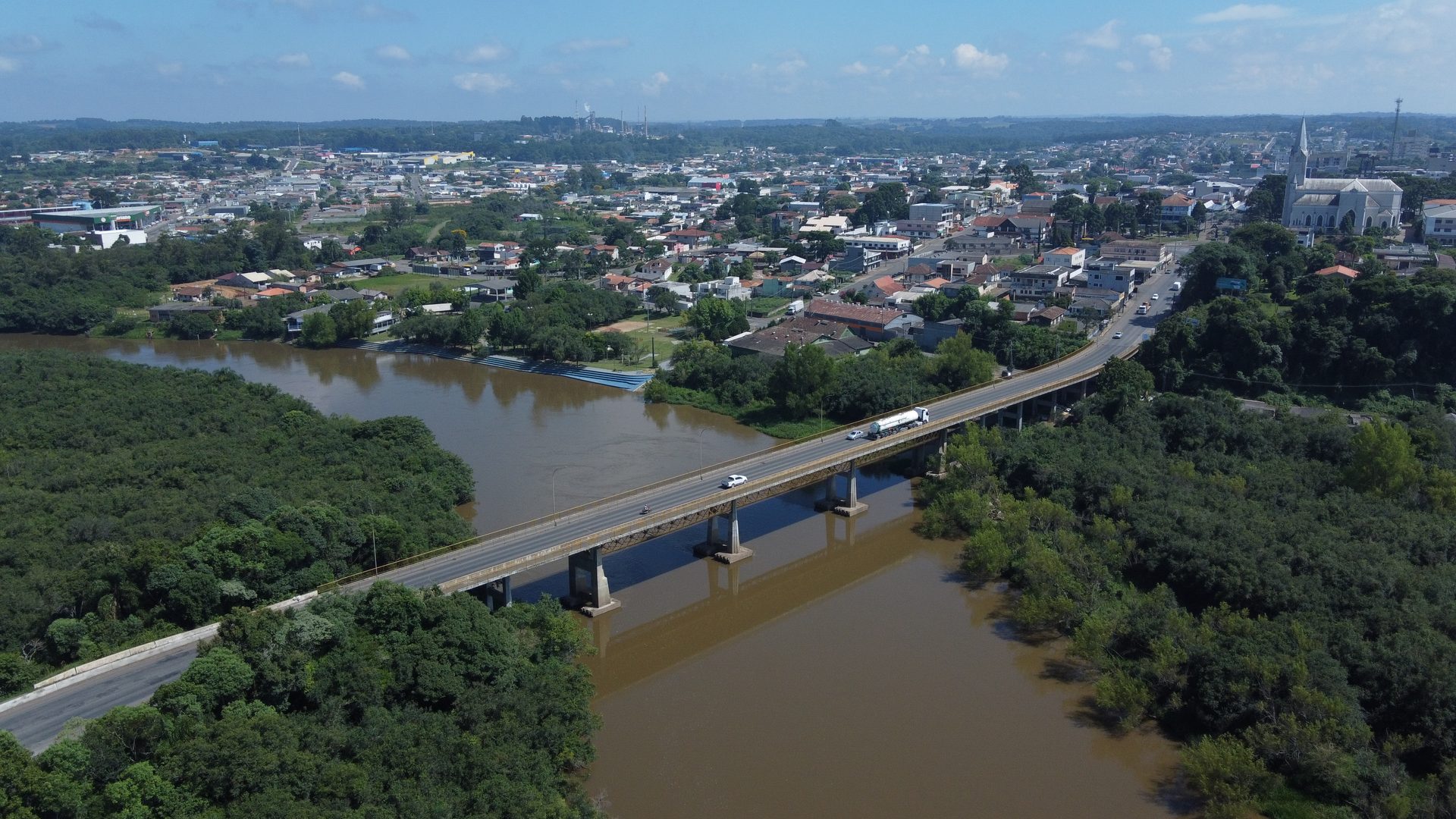 Vista aérea da ponte de entrada de São Mateus do Sul sobre o Rio Iguaçu com a cidade ao fundo