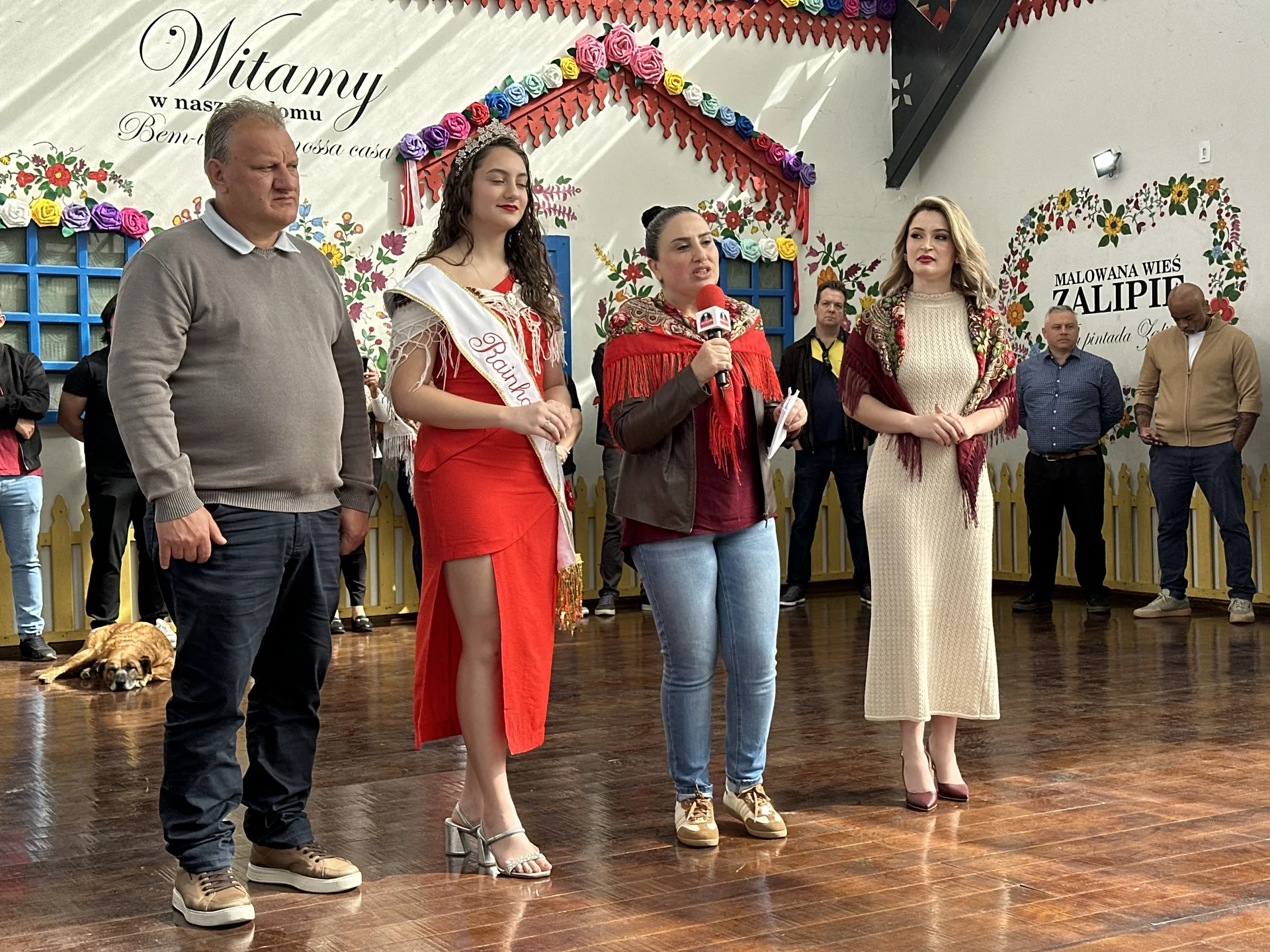 Participantes da cerimônia de abertura em espaço decorado com elementos da cultura polonesa.
