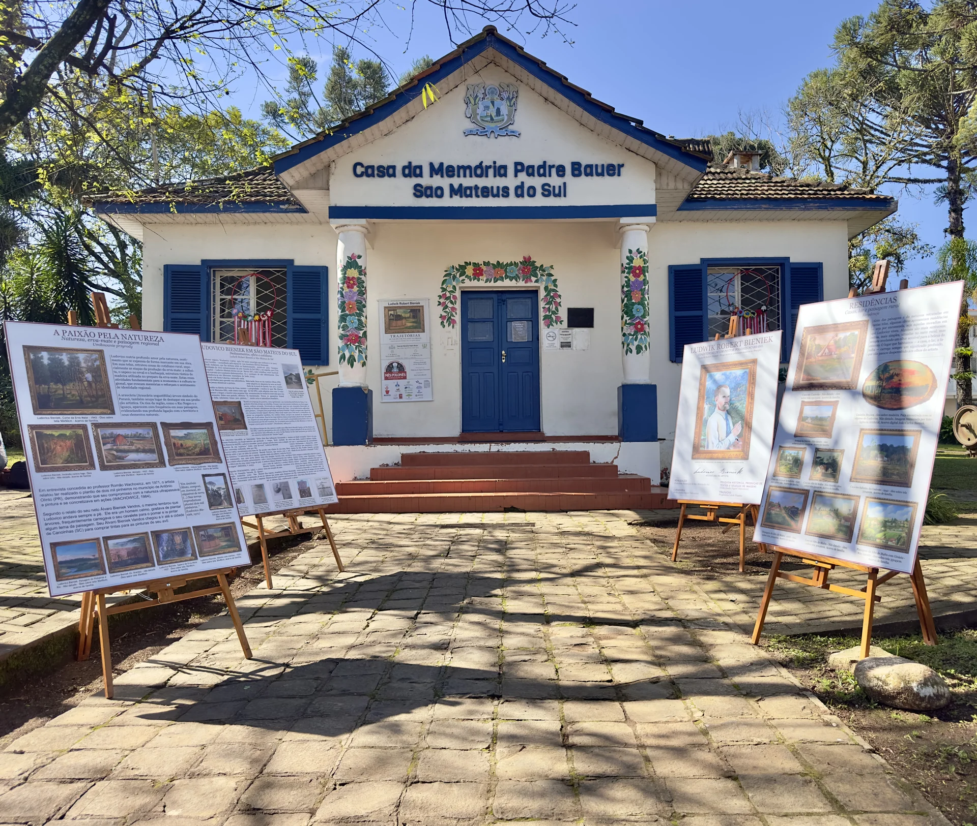Fachada da Casa da Memória Padre Bauer com painéis e obras da exposição sobre Ludovico Bieniek.